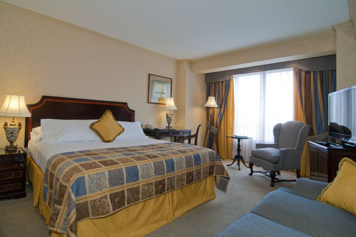 Een hotelkamer met een groot bed, een bureau, een stoel en een televisie.