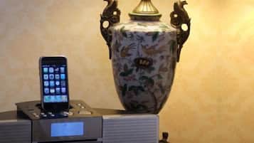 Un teléfono inteligente en una base de carga, un jarrón decorativo y una pequeña mesa con una lámpara.