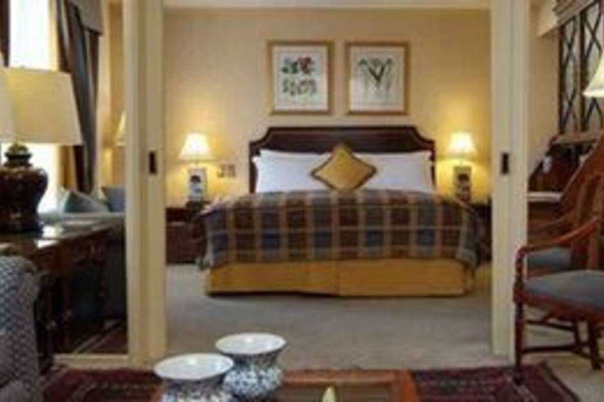 Een hotelkamer met een bed, een bureau, een stoel en twee lampen.