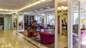 A spacious lobby with a polished floor, a large bookshelf, and comfortable seating areas.