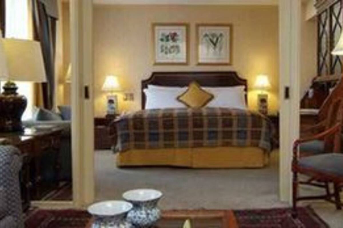 Een hotelkamer met een bed, een bureau, een stoel, een lamp en een klein tafeltje.