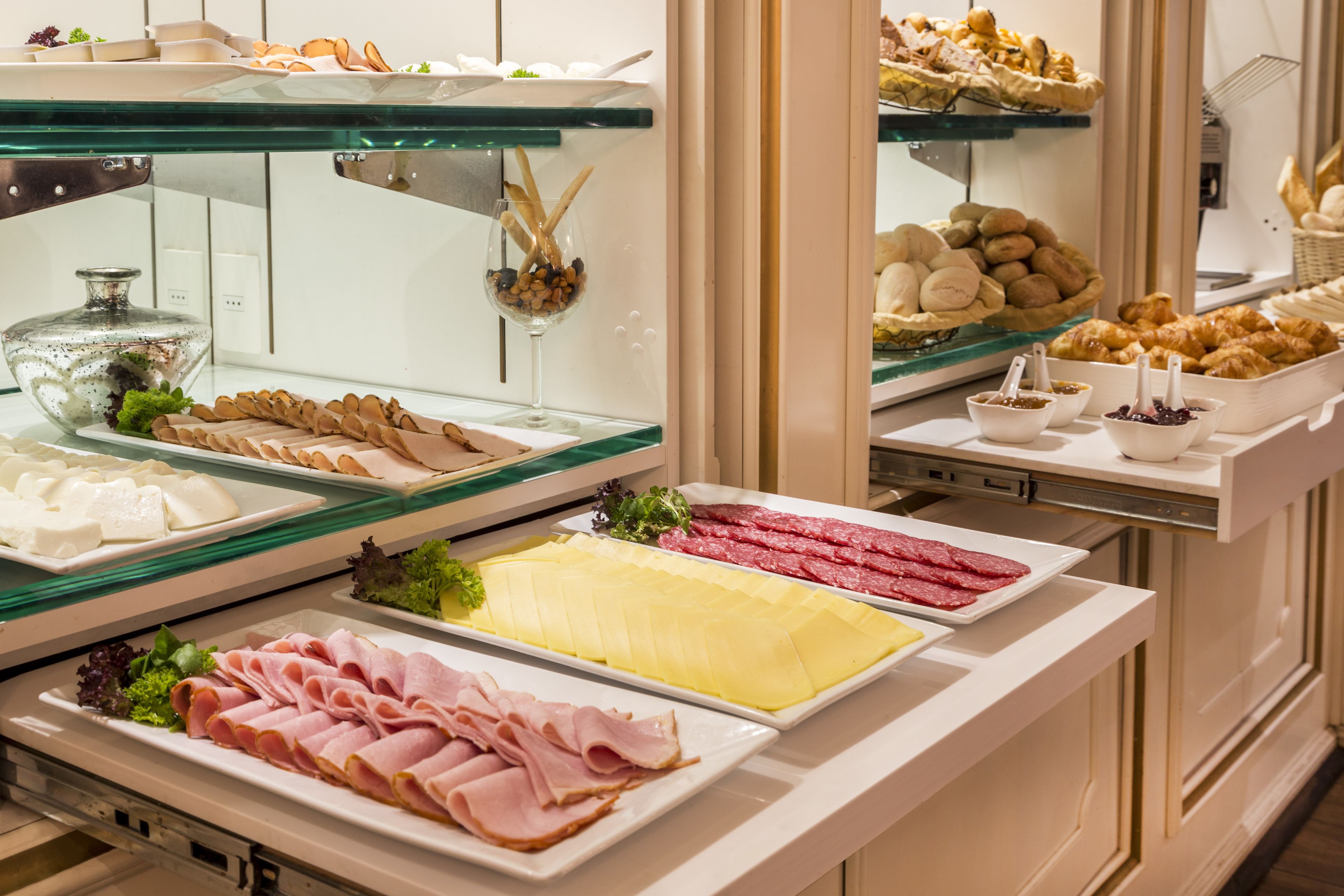 A buffet with various food items including meats, cheeses, and pastries.