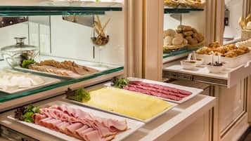 A buffet with various food items including meats, cheeses, and pastries.