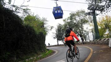 Un ciclista en una carretera con un teleférico sobre él.