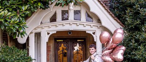 A person standing in front of a building with a brick facade and a decorative entrance.