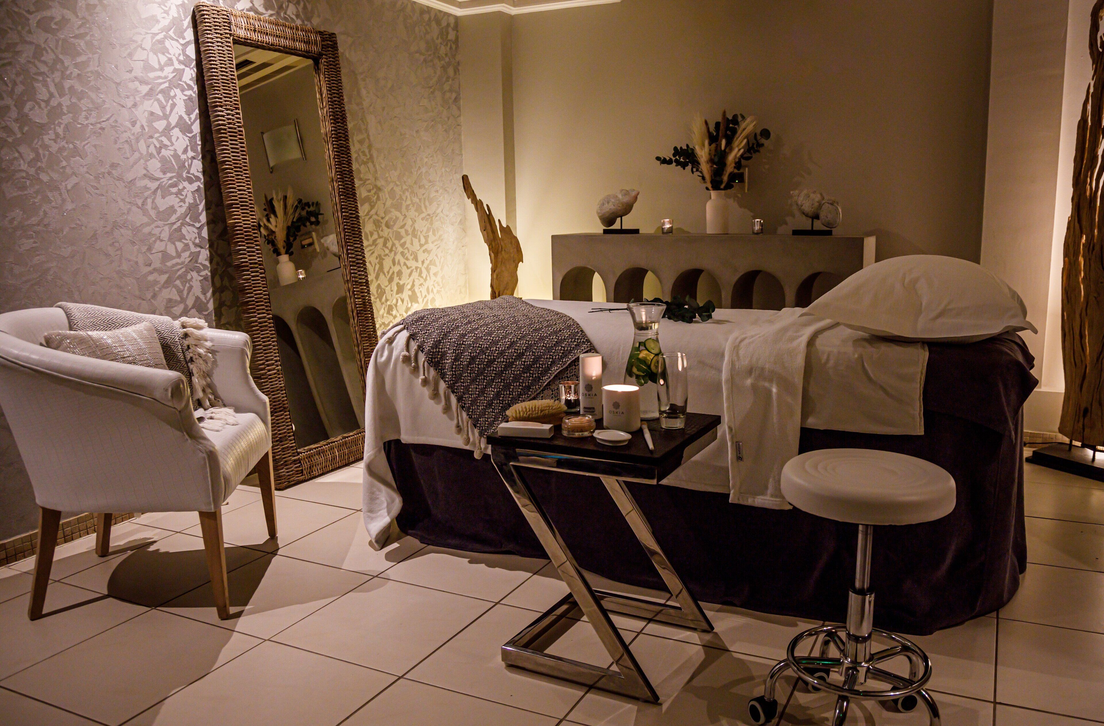 A well-lit room with a bed, a chair, a vanity table, and a mirror.