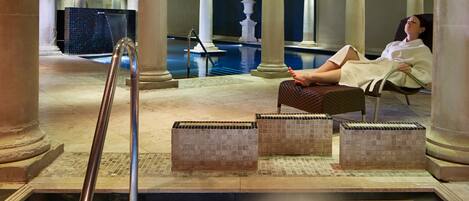 Un espace de détente avec une piscine, des colonnes et une personne se relaxant sur une chaise.