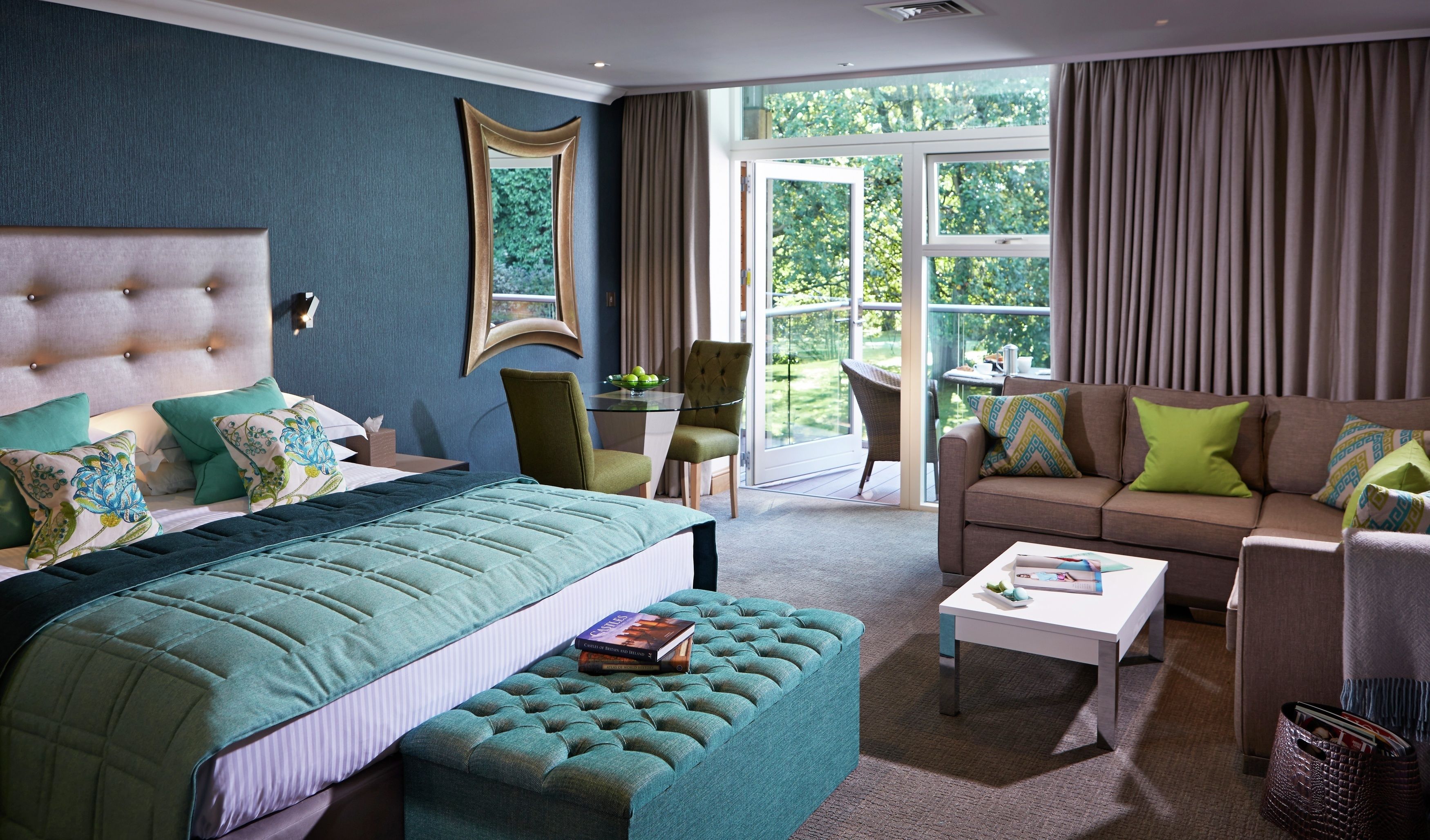 Ein geräumiges Schlafzimmer mit einem großen Bett, einem Sofa, einem Couchtisch und Blick auf den Garten durch das Fenster.