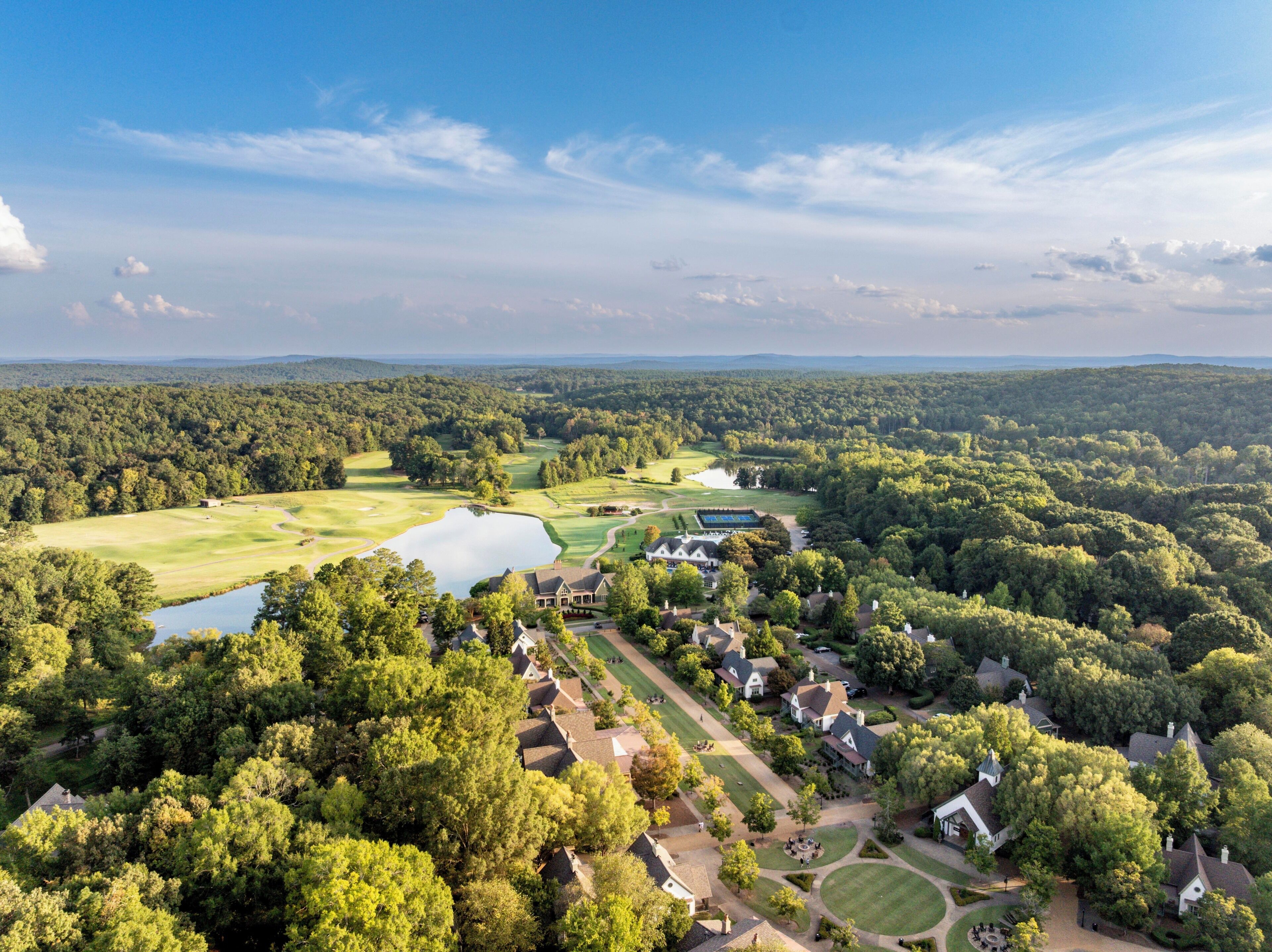 An aerial view of a residential area with houses, a golf course, and a lake.