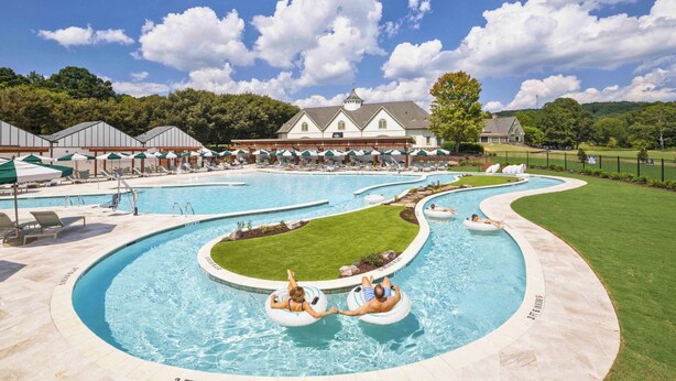 Een resort met meerdere zwembaden, terrasjes en een groot gebouw op de achtergrond.