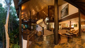 A spacious lobby with a stone floor, wooden beams, and a staircase leading to upper levels. - Thala Beach Nature Reserve (Oak Beach)