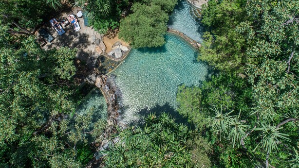 An aerial view of a natural pool surrounded by dense foliage, with a small structure and seating area visible. - Thala Beach Nature Reserve (Oak Beach)