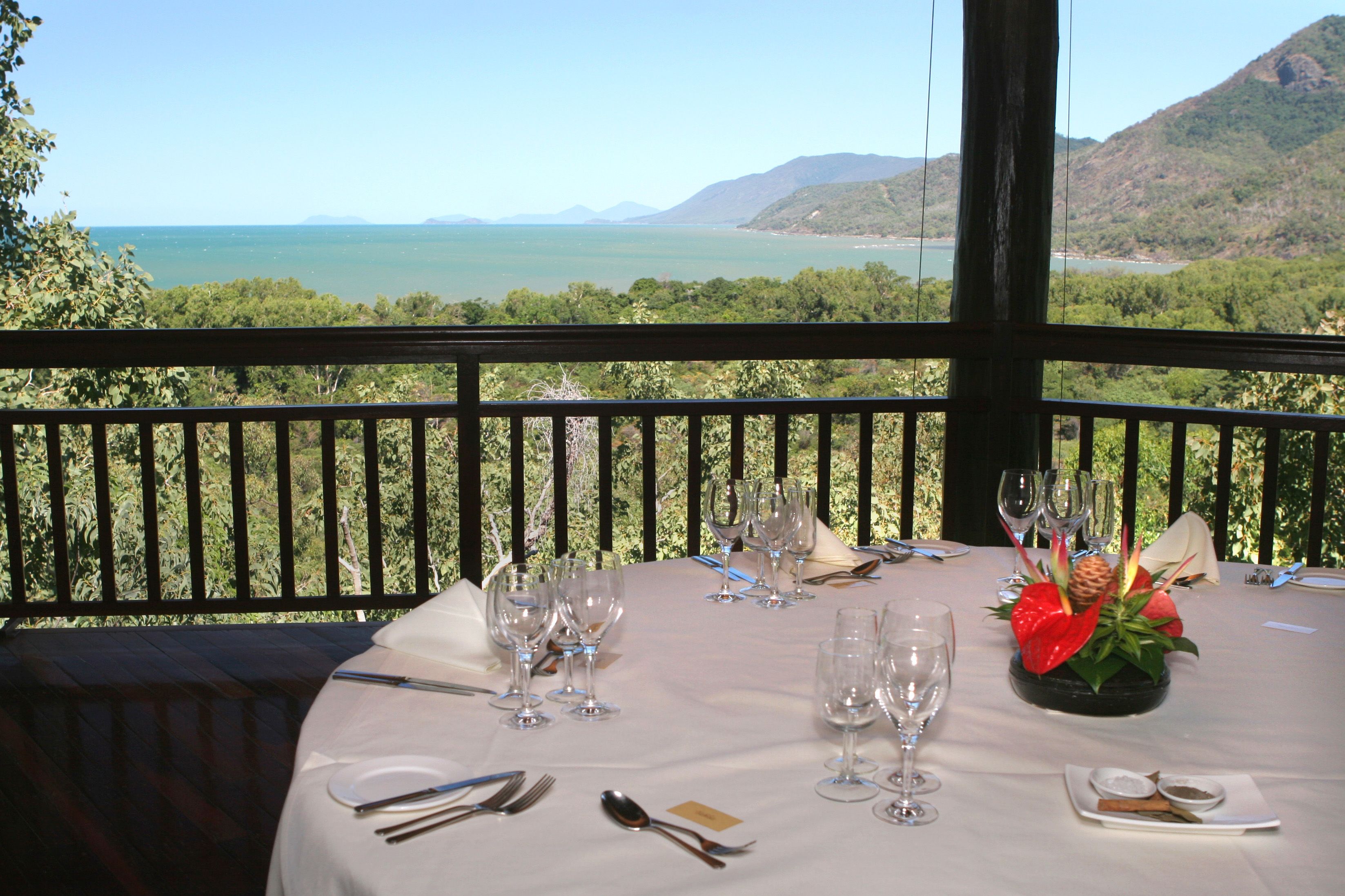 A table set for dining with a scenic view of a lake and mountains.