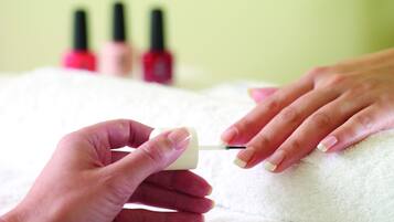 A close-up of a person painting a nail with a nail polish brush.