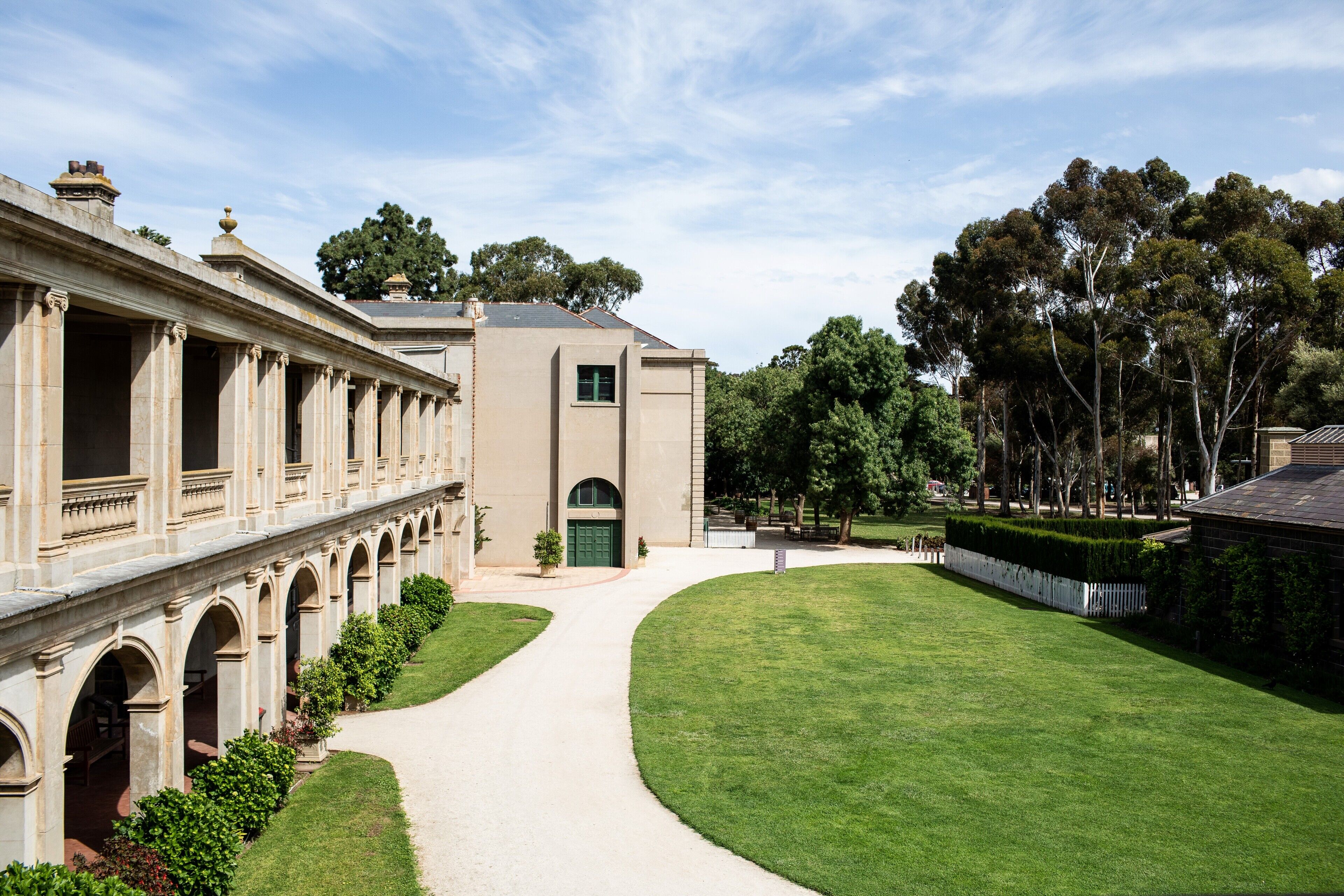 A classical building with a central courtyard, arched walkways, and a well-maintained lawn.
