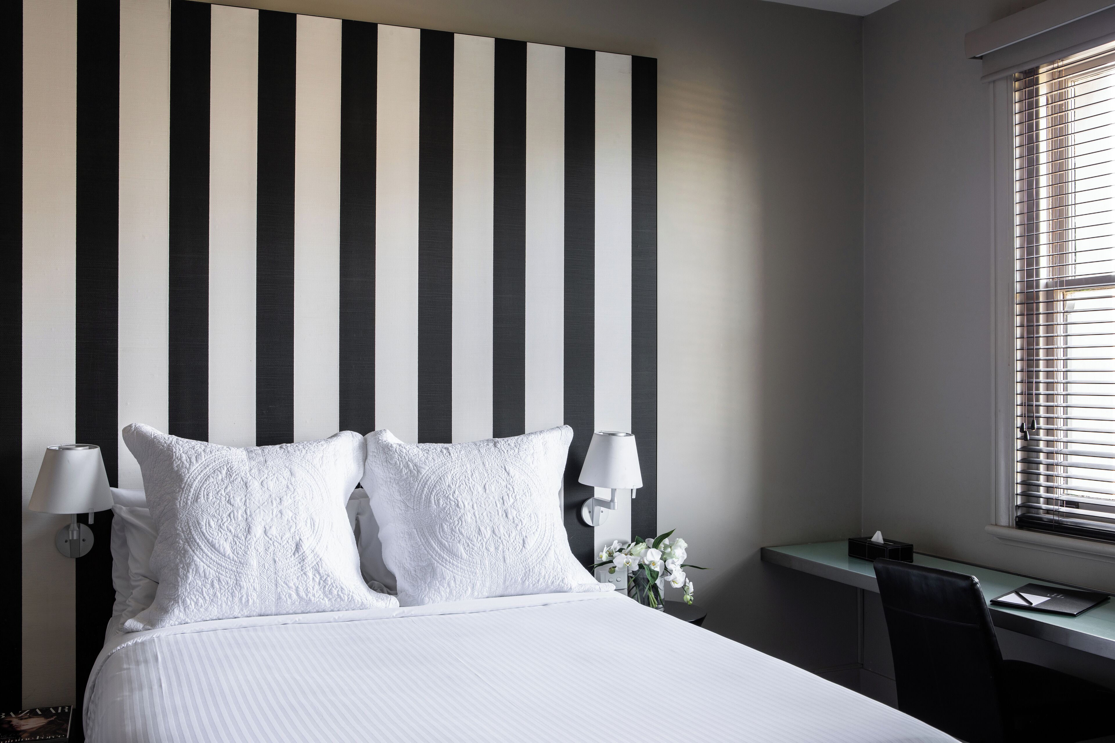 Una habitación de hotel con cama, escritorio y ventana con persianas.