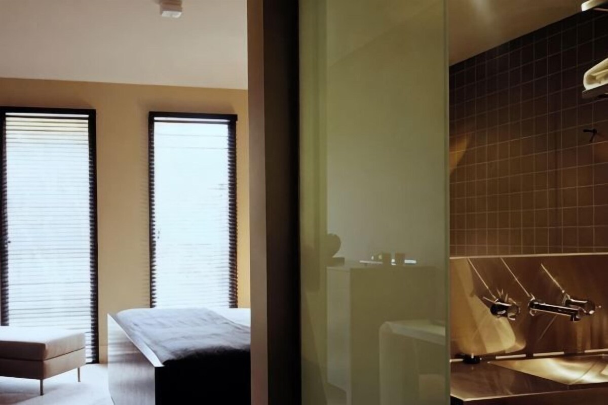 Une chambre d’hôtel moderne comprenant un lit, un petit coin salon et une salle de bain avec douche.
