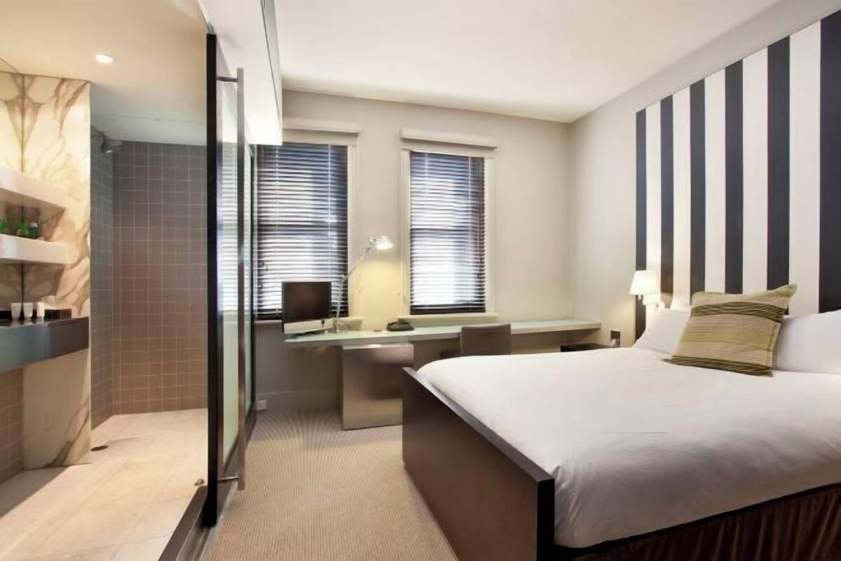 Una habitación de hotel moderna con una cama grande, un escritorio y una zona de ducha.