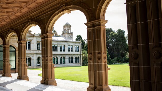 A covered walkway with ornate columns, leading to a building with a clock tower. - Lancemore Mansion Hotel Werribee Park (Werribee South)
