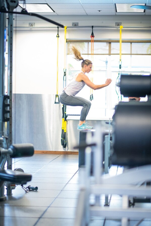 A gym with exercise equipment, including TRX handles and weight machines.