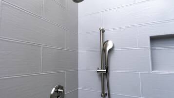Ducha con cabezal de ducha de mano y panel de control en la pared.