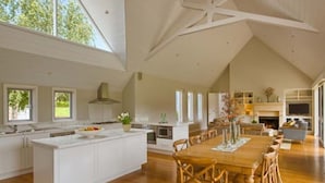 A spacious kitchen with a large island, wooden dining table, and chairs. - Cape Lodge (Wilyabrup)
