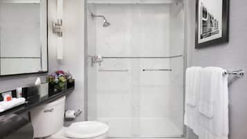 A modern bathroom with a glass-enclosed shower, a toilet, and a sink with toiletries.