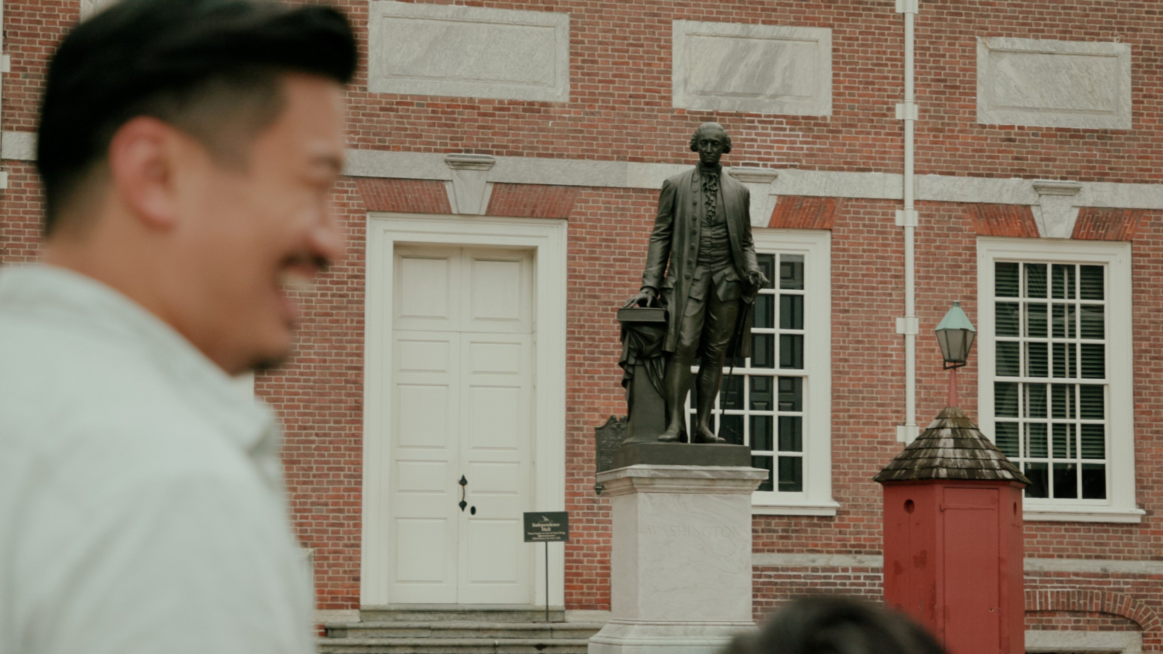 A statue in front of a brick building with a white door and windows.