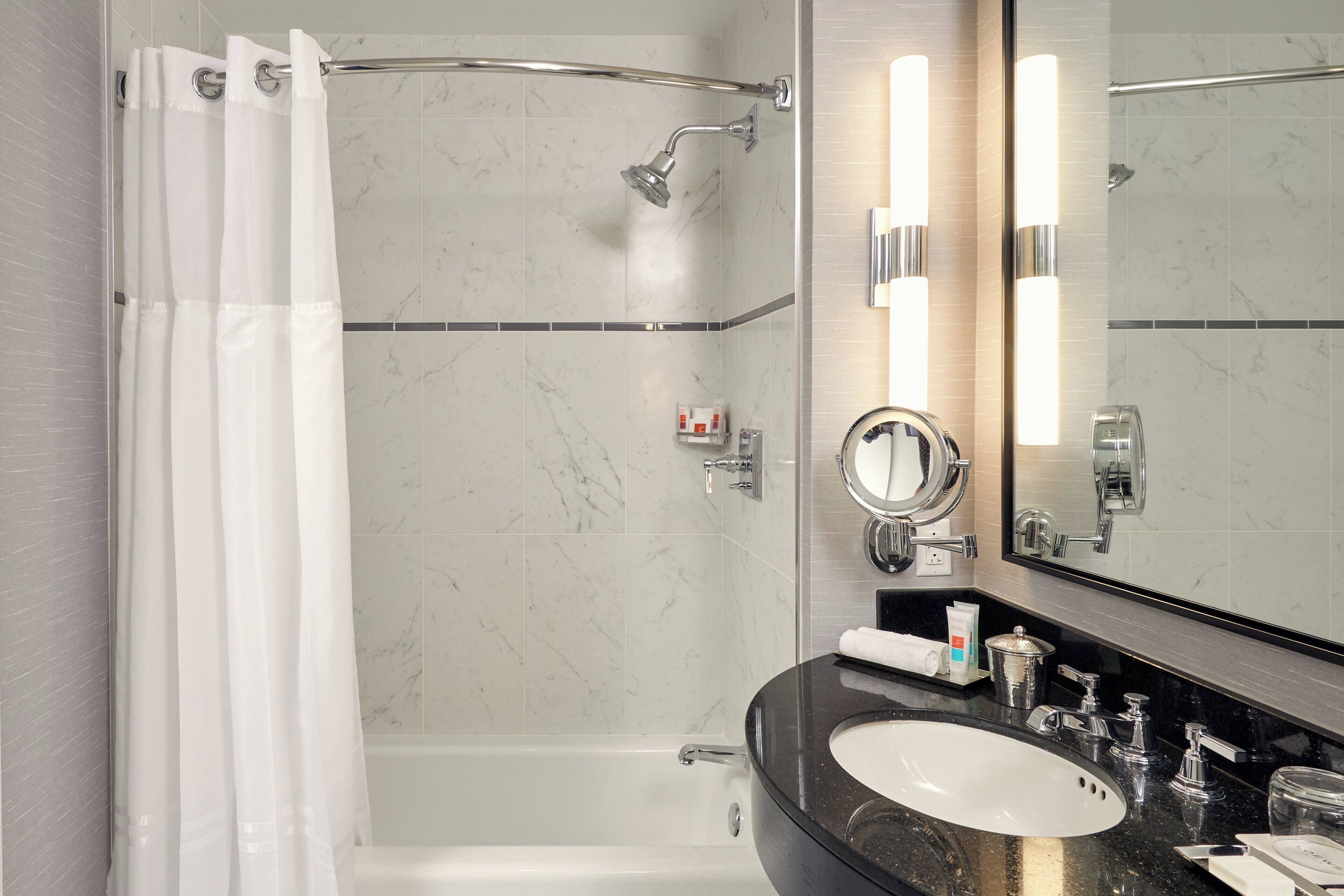 Une salle de bain moderne équipée d’une douche, d’une baignoire, d’un meuble-lavabo et d’un grand miroir.