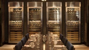 A dining area with a long table set for six, flanked by wine coolers.