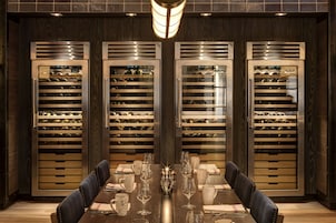 A dining area with a long table set for six, flanked by wine coolers.