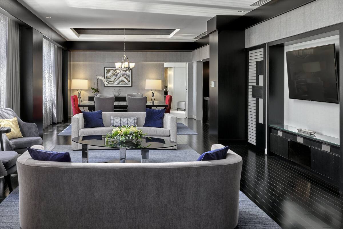 A modern living room with a sofa, chairs, a coffee table, and a TV.