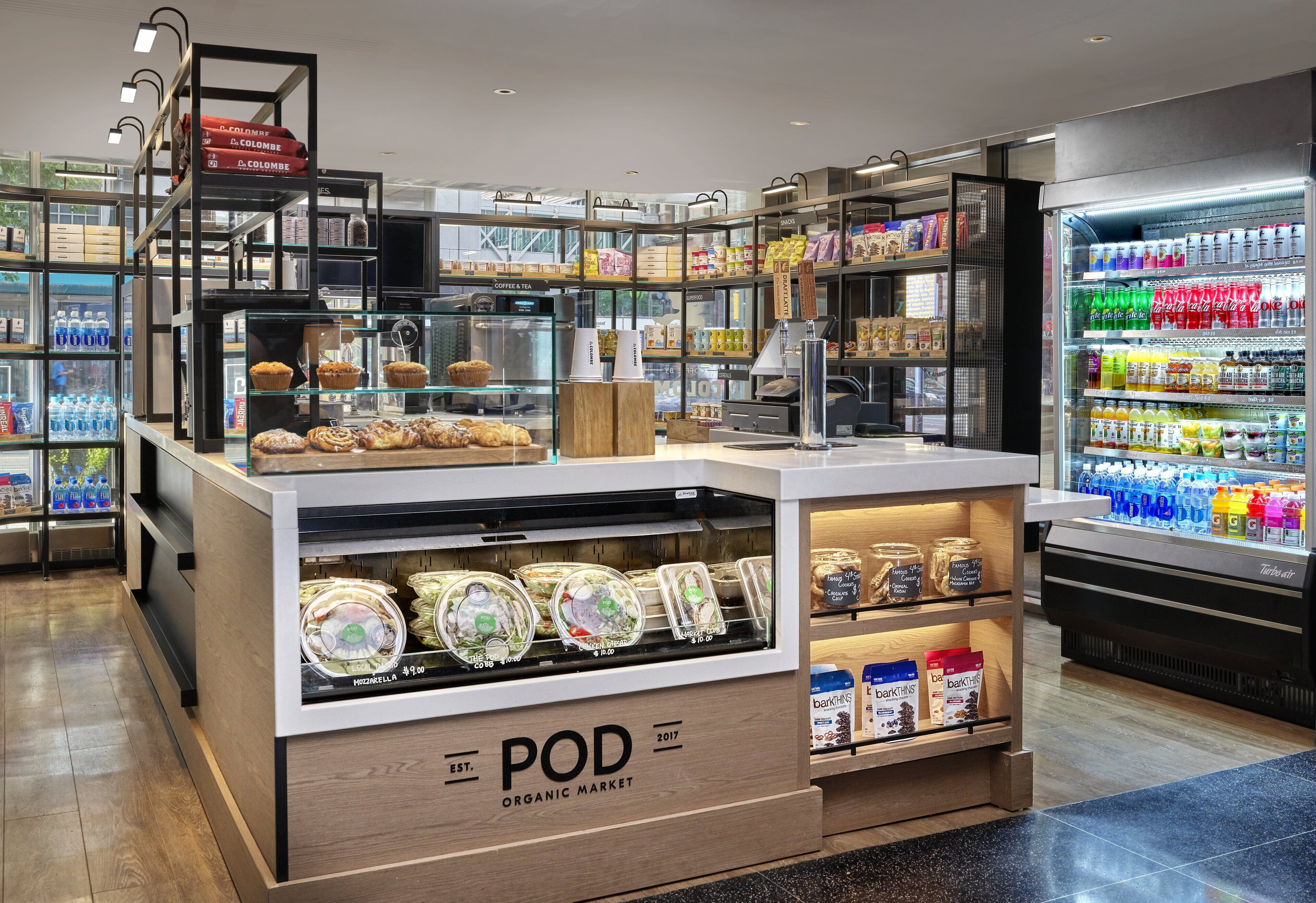 A POD Organic Market with a display of pastries, jars, and a refrigerated section with beverages.