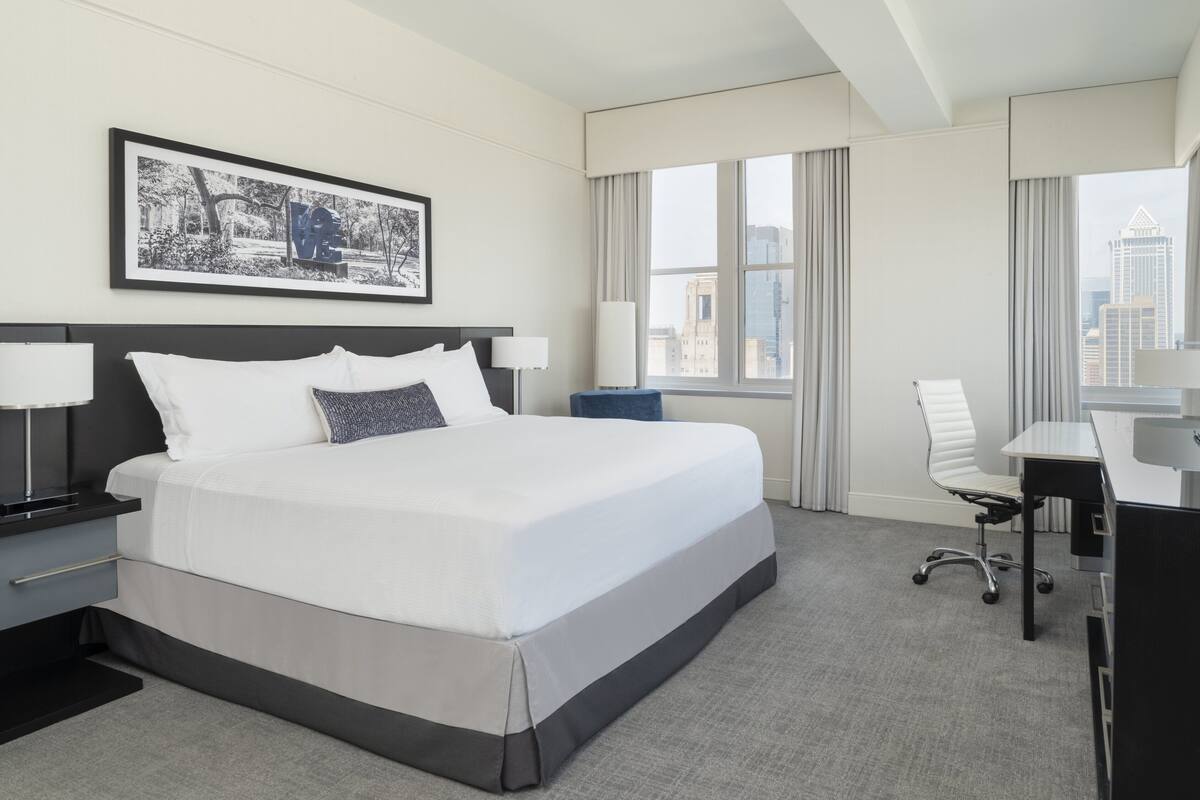 A modern hotel room with a large bed, a desk, and a chair.