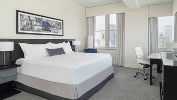 A modern hotel room with a large bed, a desk, and a chair.