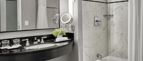 A modern bathroom with a black sink, a mirror, a shower, and a bathtub.