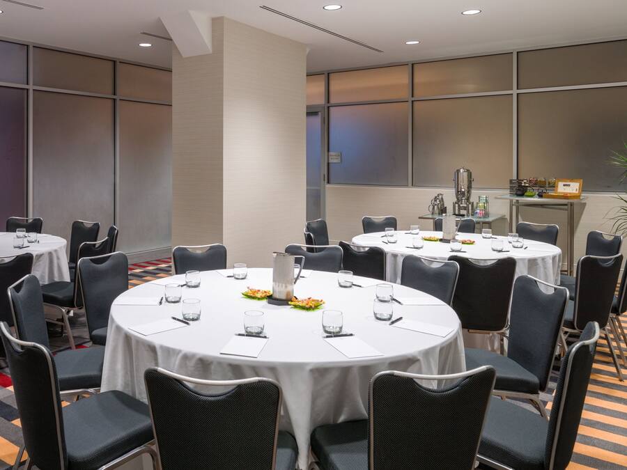 A conference room with round tables, chairs, and a coffee machine.