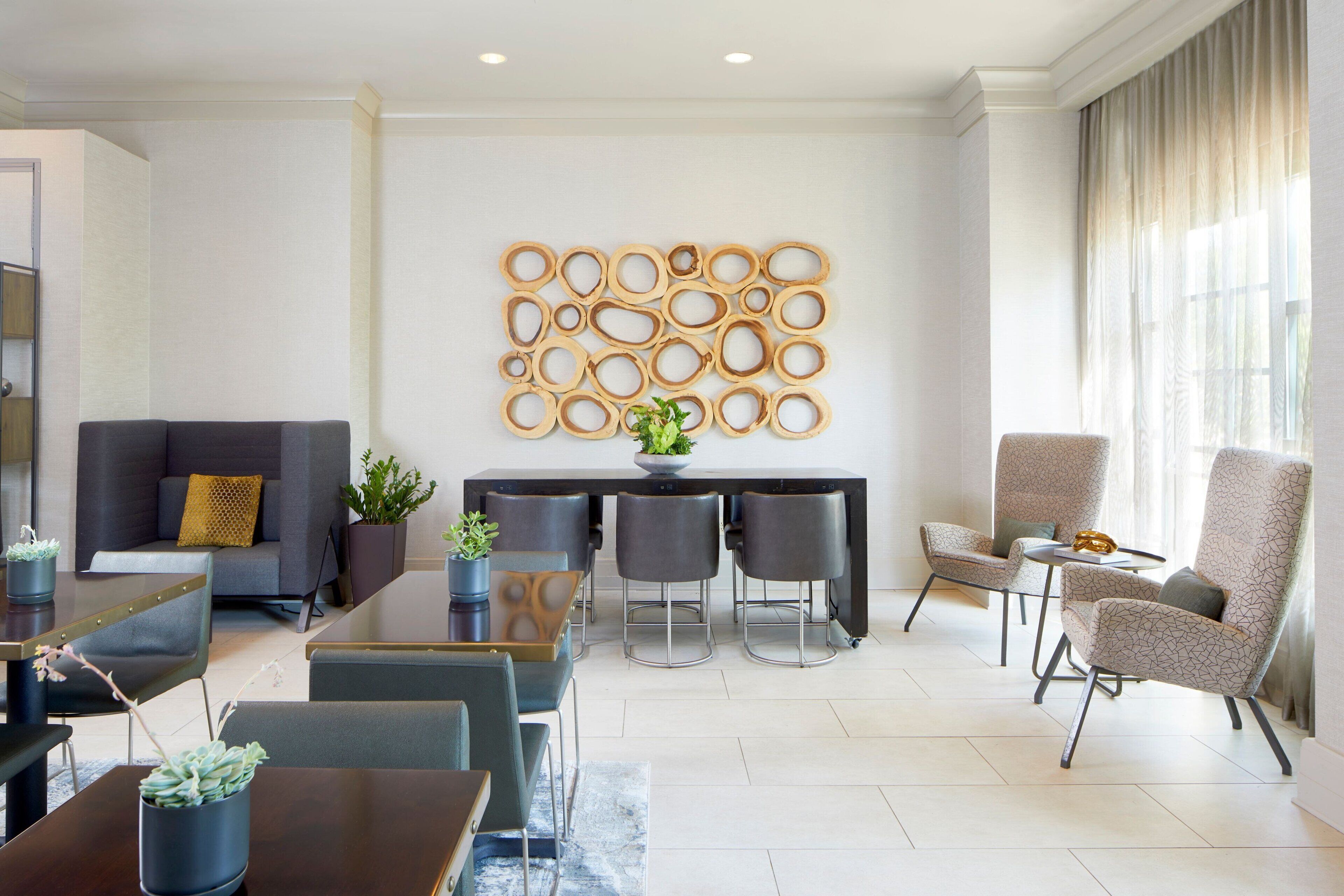 Un salon moderne comprenant un canapé, une table à manger, des tabourets de bar et un élément décoratif mural.