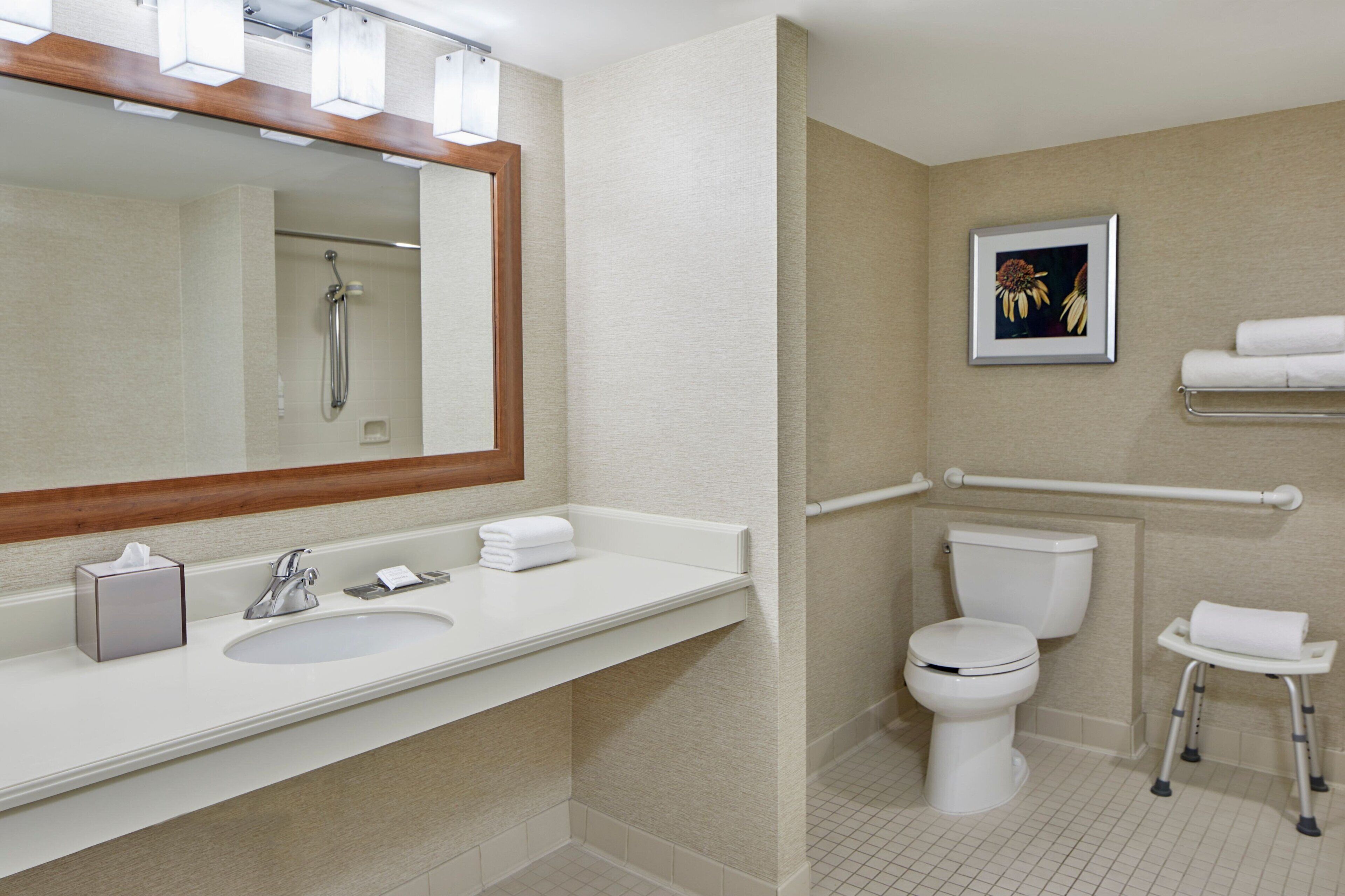 Un baño moderno con lavamanos, espejo, inodoro y ducha.