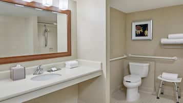 Un baño moderno con lavamanos, espejo, inodoro y ducha.