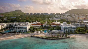 Un complejo turístico frente al mar con varias edificaciones, una playa y una zona de piscina.