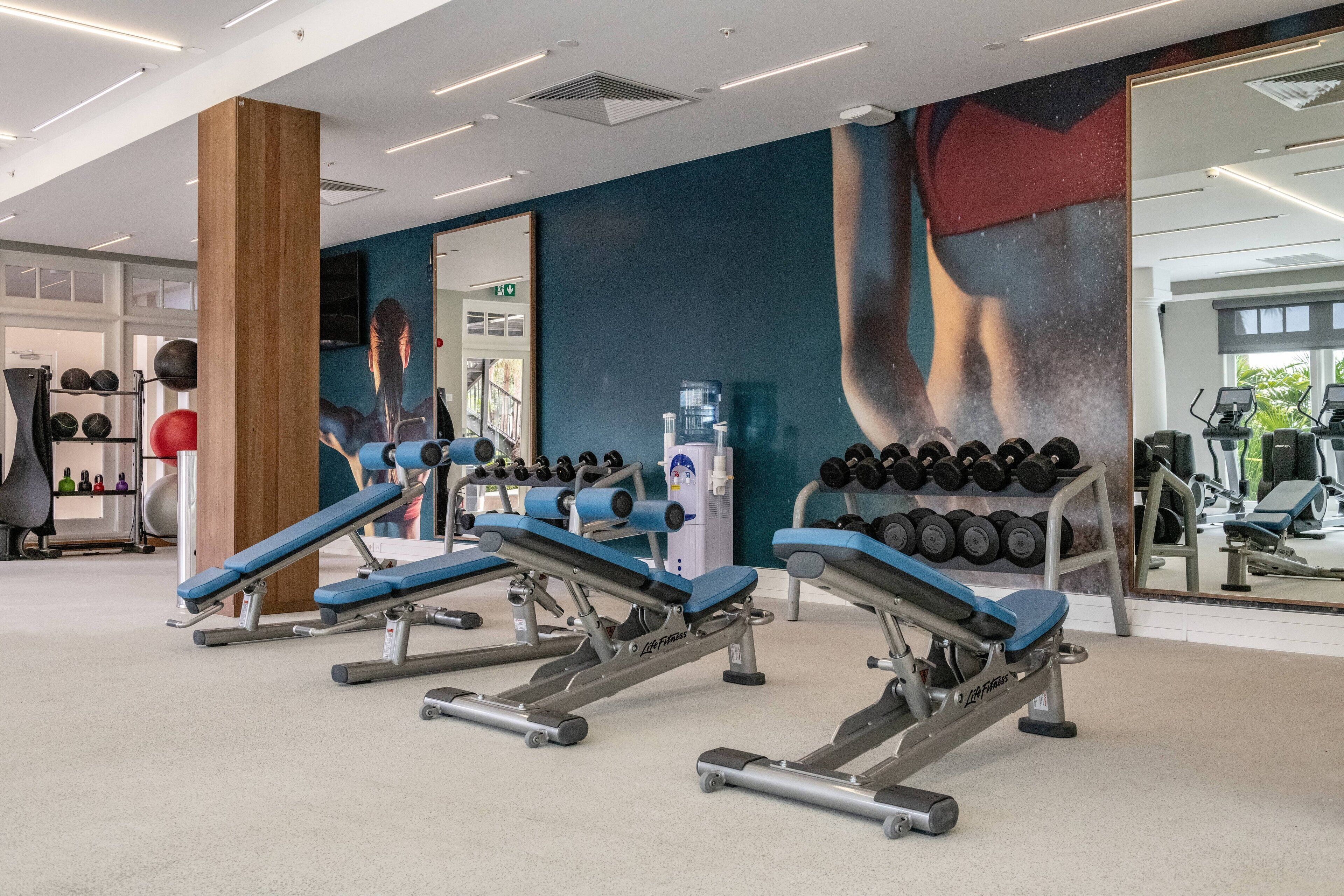 A gym with exercise equipment, a water dispenser, and a large mirror.