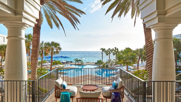 Ein Balkon mit Pool, Palmen und Meerblick.