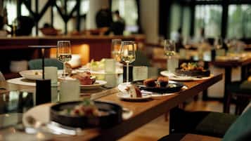 Un comedor con mesas dispuestas para comidas, copas de vino blanco y diversos platos.