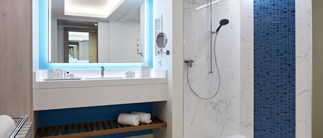 A modern bathroom with a shower, a built-in sink, and a mirror with integrated lighting.