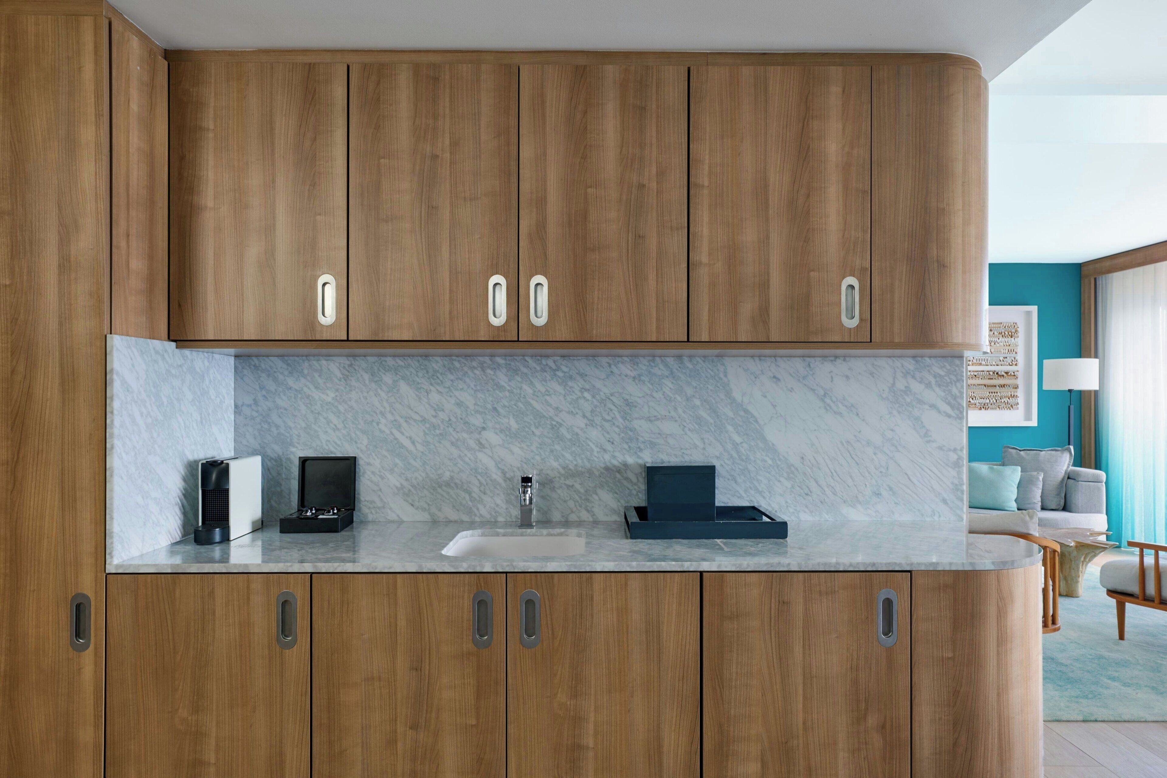 Una cocina moderna con armarios de madera, encimera de mármol y pileta integrada.