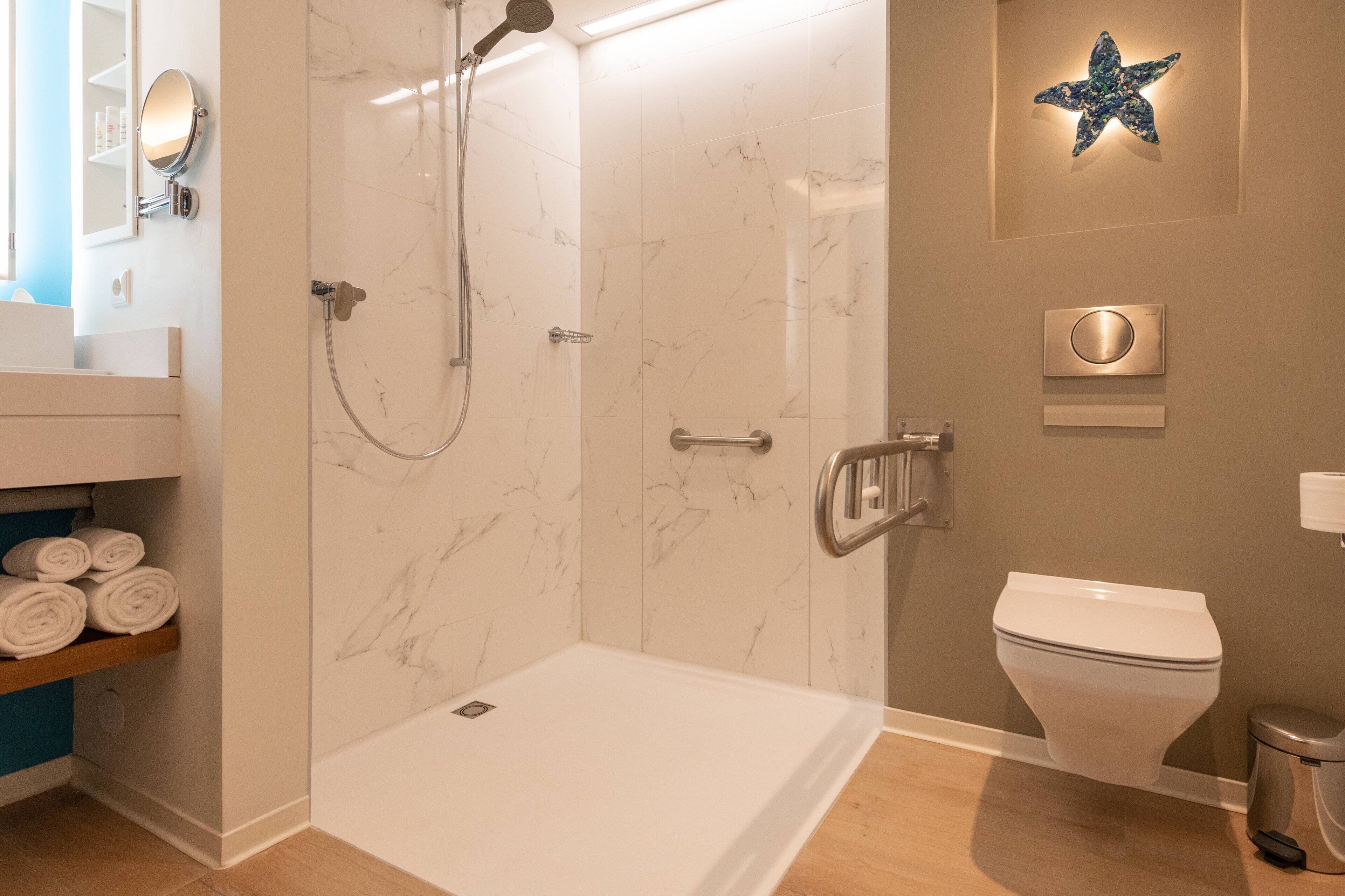 A bathroom with a shower, toilet, and a shelf with towels.