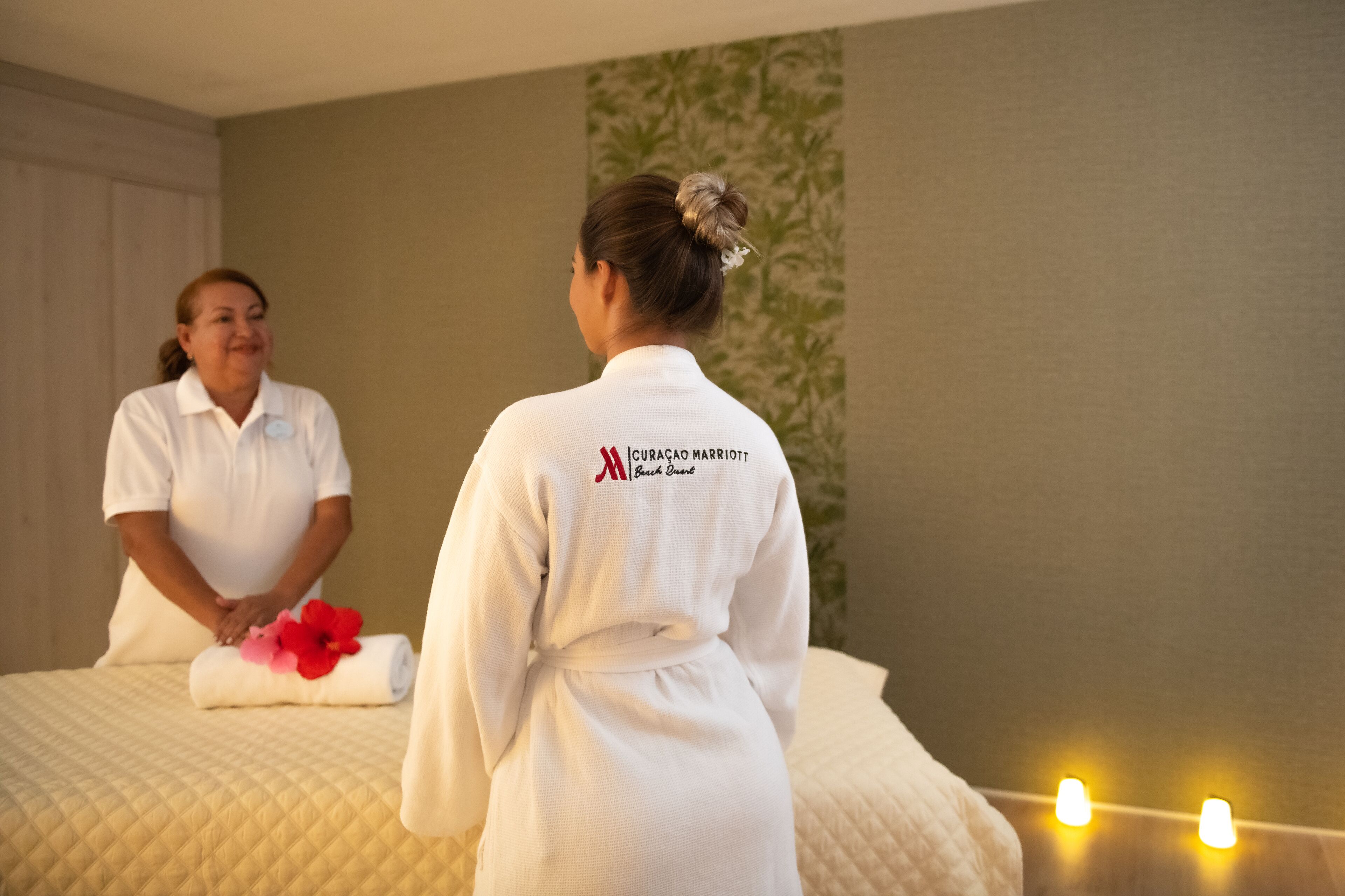 Ein Hotelzimmer mit Bett, einem Handtuch mit Blumen und einer Person in einem Bademantel.