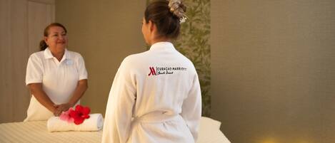 Ein Hotelzimmer mit Bett, einem Handtuch mit Blumen und einer Person in einem Bademantel.