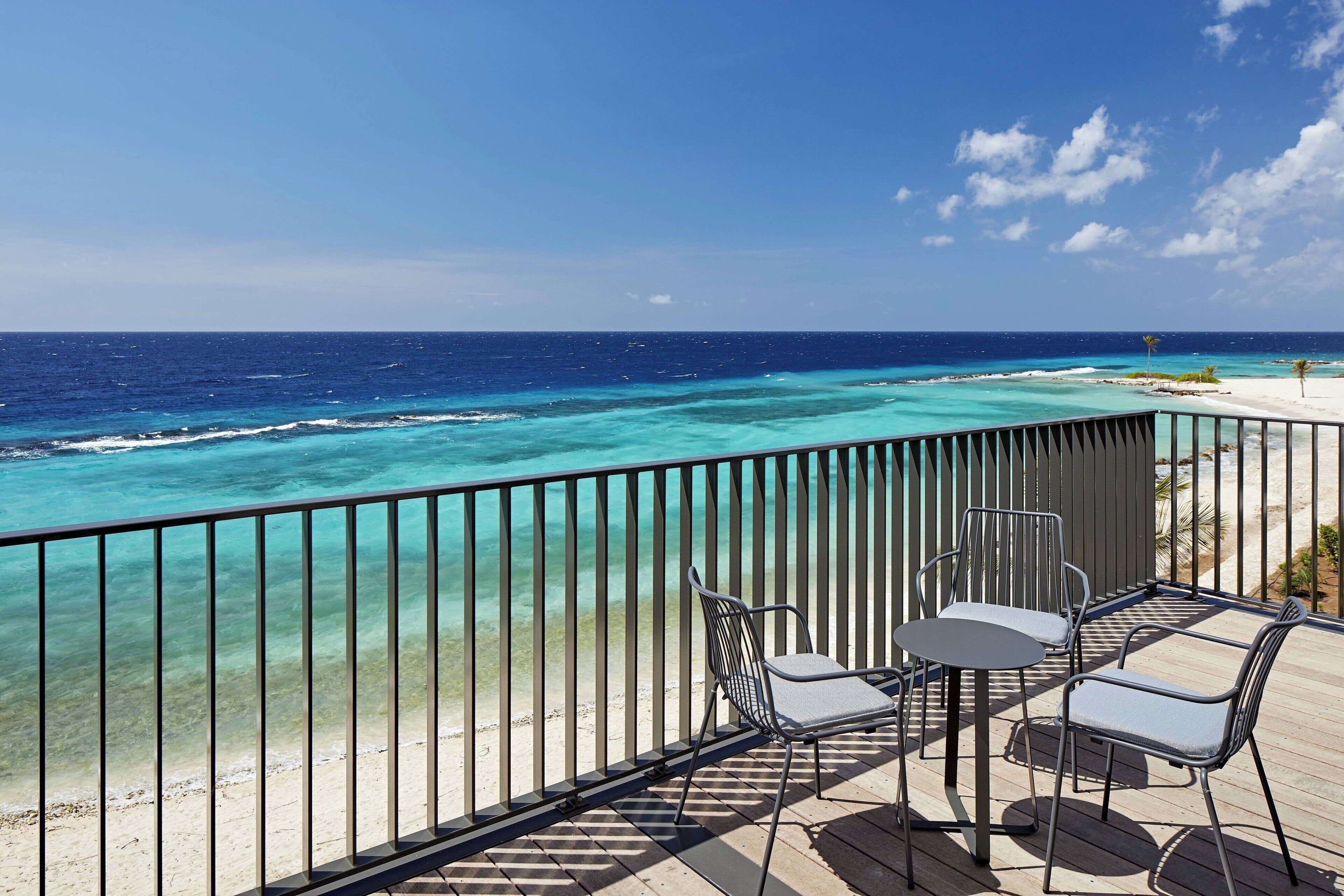 A deck with a view of turquoise waters and a sandy beach.